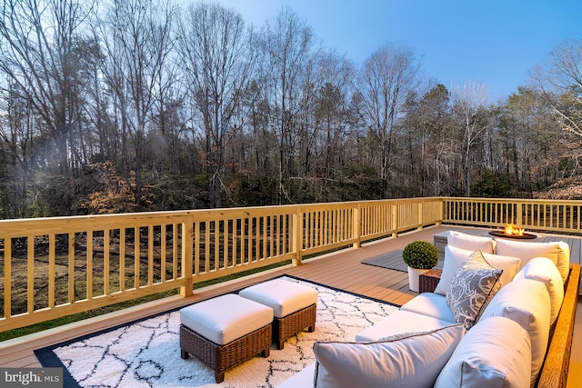 wooden deck featuring an outdoor living space with a fire pit