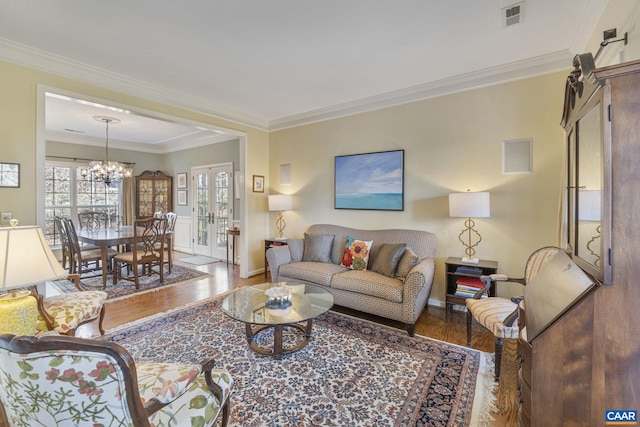 living room featuring visible vents, crown molding, a chandelier, french doors, and wood finished floors