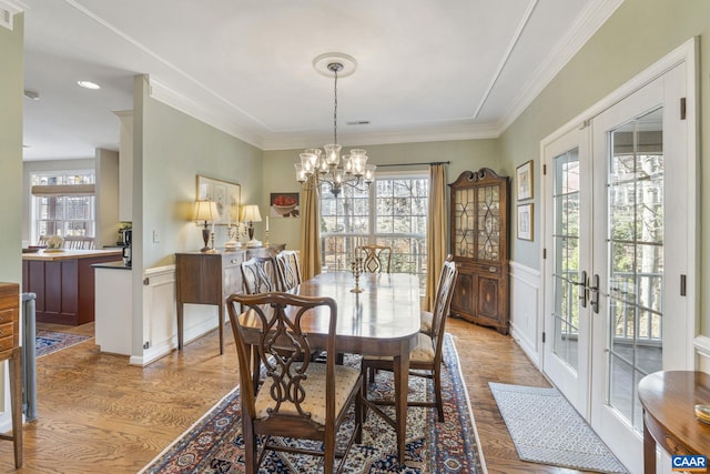 dining room featuring french doors, a healthy amount of sunlight, a wainscoted wall, and ornamental molding