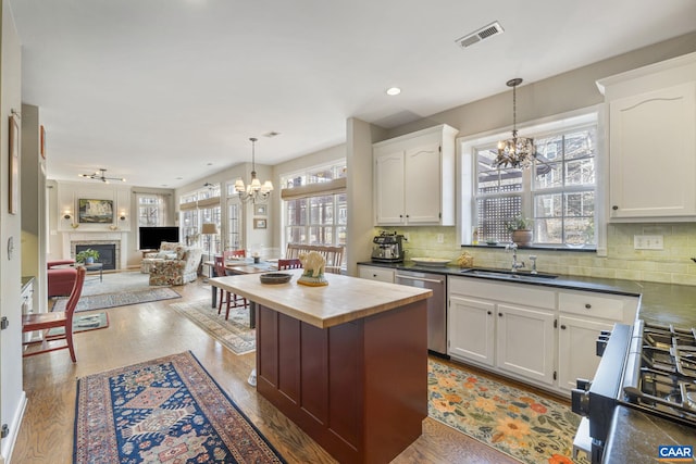 kitchen featuring butcher block countertops, a sink, range with gas stovetop, stainless steel dishwasher, and a chandelier