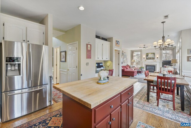 kitchen featuring wood finished floors, white cabinets, stainless steel fridge with ice dispenser, wooden counters, and a chandelier