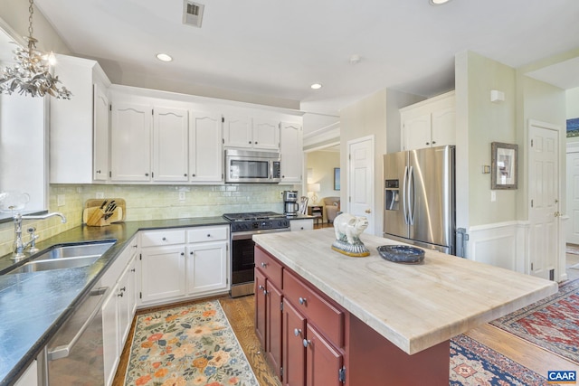 kitchen with visible vents, a sink, backsplash, light wood-style floors, and appliances with stainless steel finishes