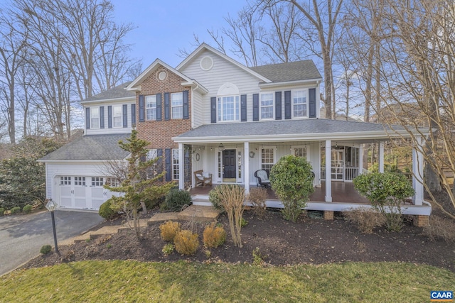 view of front facade featuring aphalt driveway, covered porch, a garage, and roof with shingles