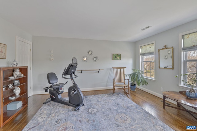 exercise area with wood finished floors, visible vents, and baseboards