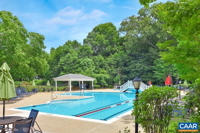 view of pool with a gazebo, a water slide, a patio, and fence