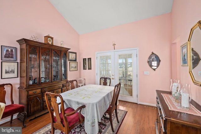 dining room with lofted ceiling, french doors, light wood-style floors, and baseboards