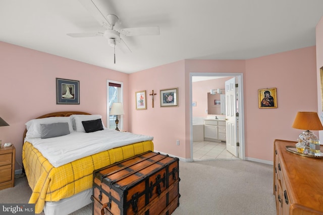 bedroom with a ceiling fan, baseboards, ensuite bath, a sink, and light carpet