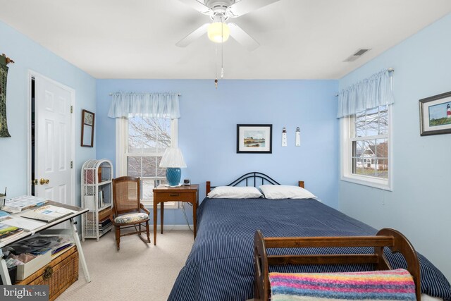 bedroom featuring multiple windows, light colored carpet, visible vents, and ceiling fan