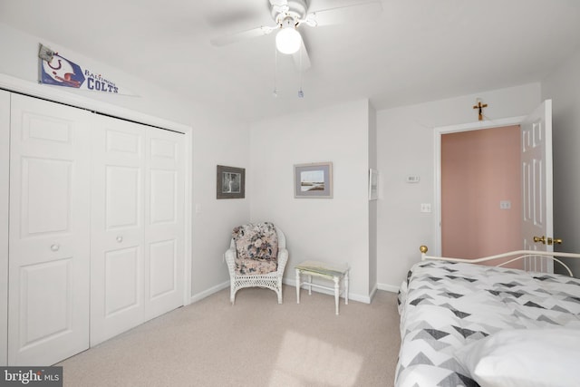 bedroom featuring a closet, light colored carpet, a ceiling fan, and baseboards