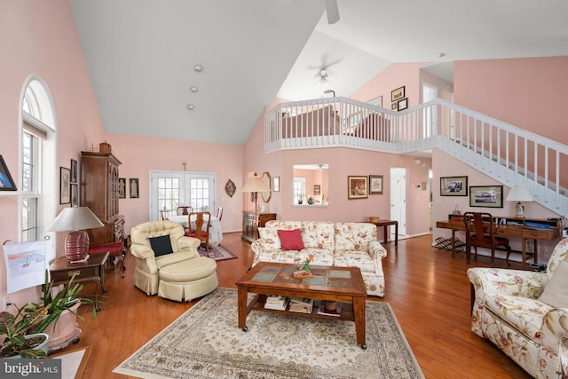 living area with stairway, high vaulted ceiling, wood finished floors, and a ceiling fan