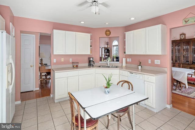 kitchen featuring white appliances, white cabinets, light tile patterned floors, and a sink