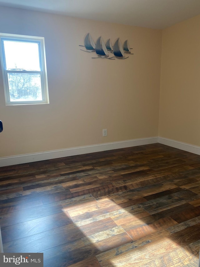 unfurnished room featuring baseboards and dark wood-style flooring