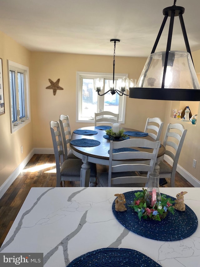 dining space featuring wood finished floors, baseboards, and a chandelier