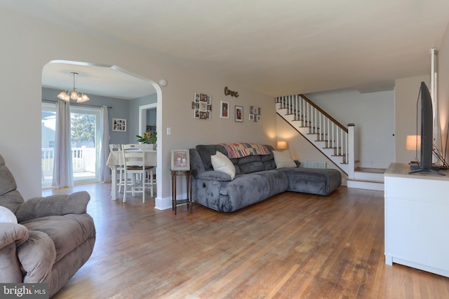 living room with arched walkways, light wood-style floors, and stairs