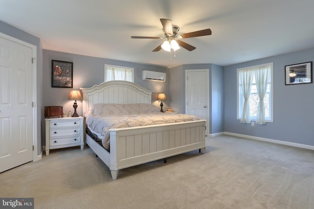 bedroom featuring a wall mounted air conditioner, baseboards, light colored carpet, and a ceiling fan