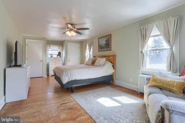 bedroom featuring baseboards, a ceiling fan, radiator heating unit, and light wood finished floors