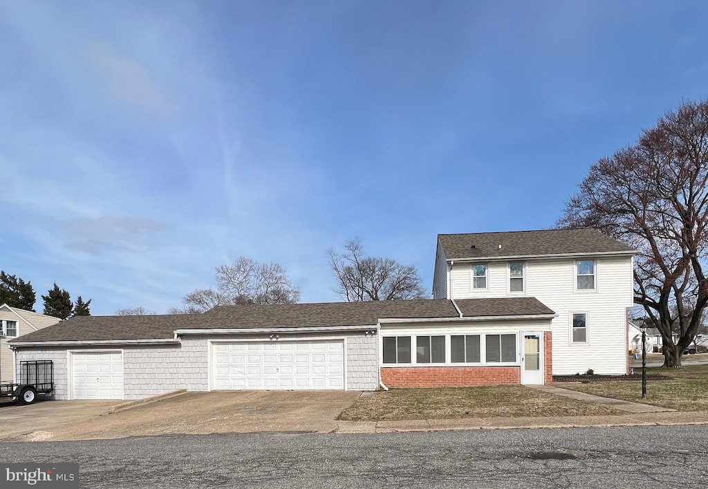 traditional-style house featuring brick siding, an attached garage, and driveway