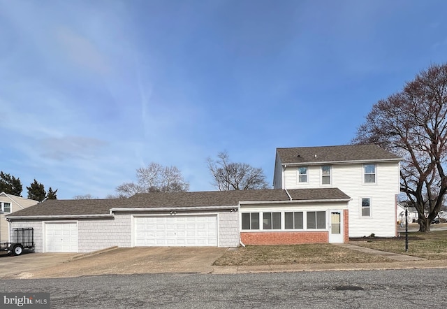 traditional-style house featuring brick siding, an attached garage, and driveway