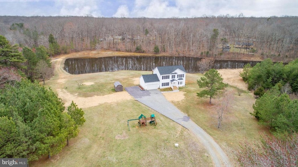 birds eye view of property with a water view and a wooded view