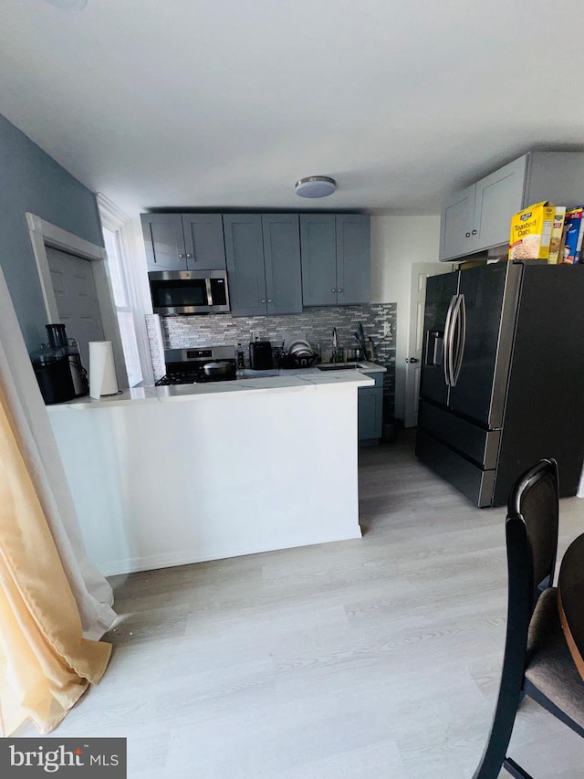 531 E Luray St, Philadelphia, PA 19120 - kitchen featuring light wood finished floors, gray cabinetry, tasteful backsplash, stainless steel appliances, and light countertops