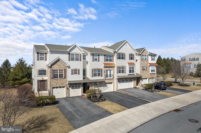 view of property featuring a garage, stone siding, driveway, and stucco siding