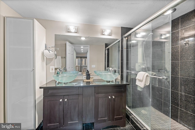 full bath with a sink, double vanity, and a shower stall