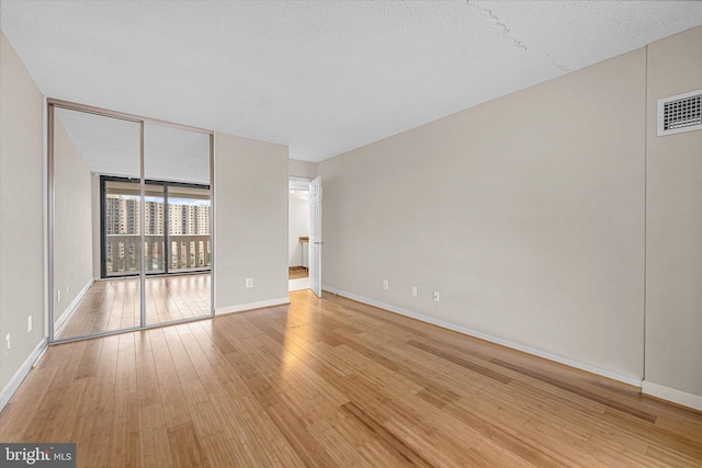 unfurnished bedroom with light wood finished floors, visible vents, baseboards, and expansive windows