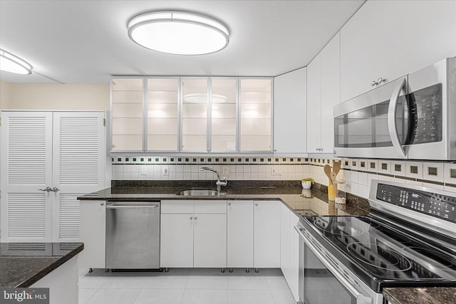 kitchen featuring backsplash, white cabinets, stainless steel appliances, and a sink