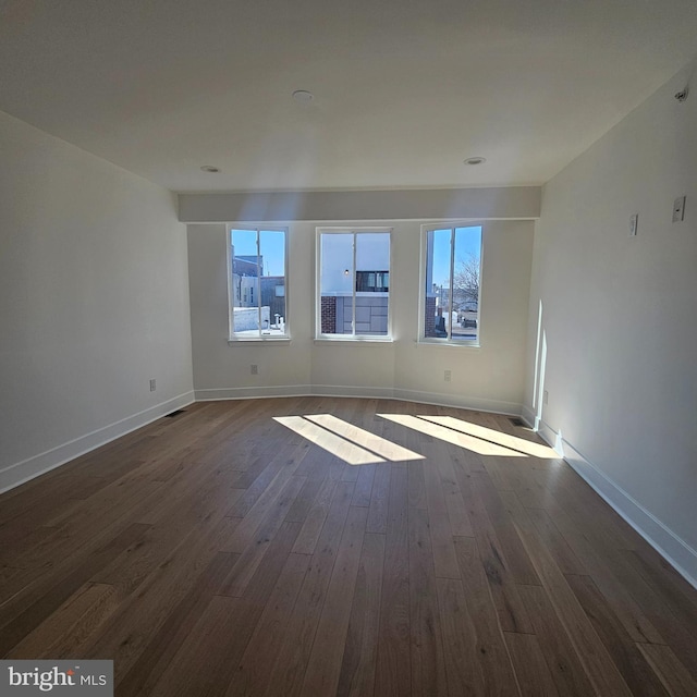 spare room with dark wood finished floors and baseboards