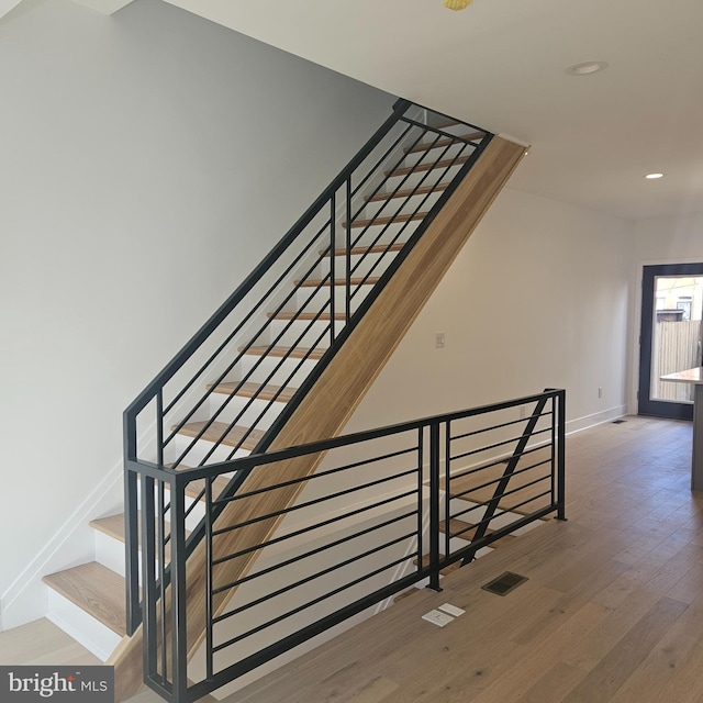 stairway with recessed lighting, wood finished floors, and baseboards