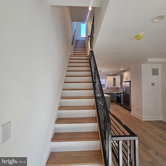 stairway featuring visible vents, recessed lighting, baseboards, and wood finished floors