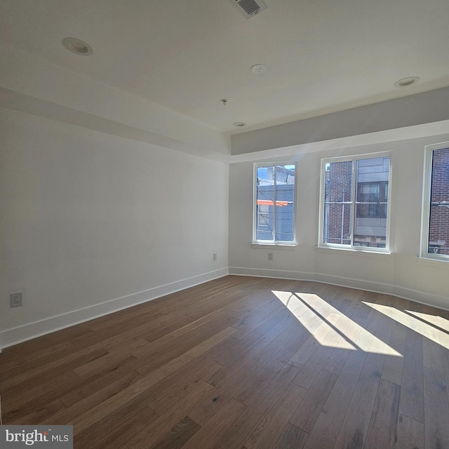 empty room with baseboards and dark wood-type flooring