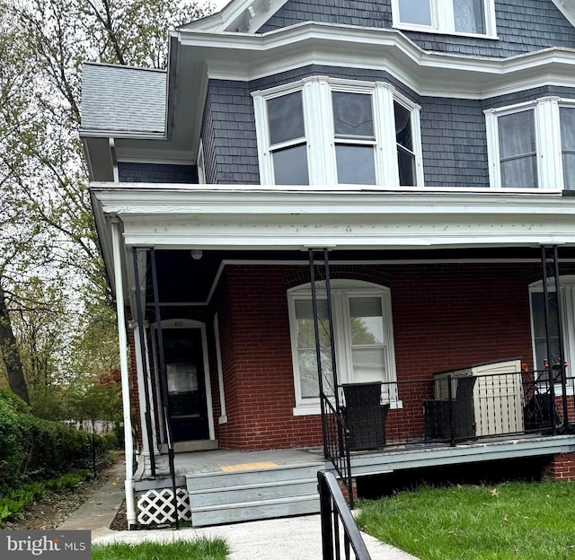 view of front of home with covered porch and brick siding