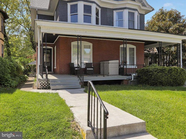 view of front of property featuring a porch, a front lawn, and brick siding
