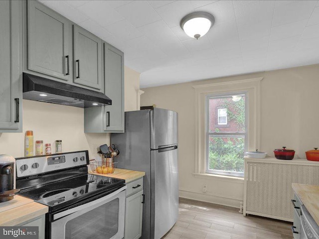 kitchen with stainless steel appliances, baseboards, light wood-type flooring, under cabinet range hood, and gray cabinetry