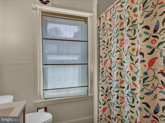 bathroom with toilet, a shower with curtain, a wealth of natural light, and vanity