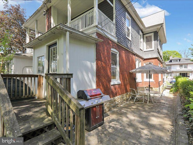 back of property with brick siding, a patio, outdoor dining area, and a balcony