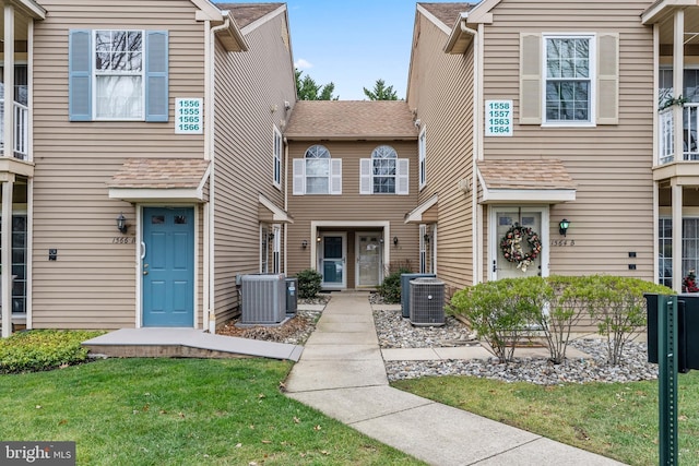 townhome / multi-family property featuring central AC unit and roof with shingles