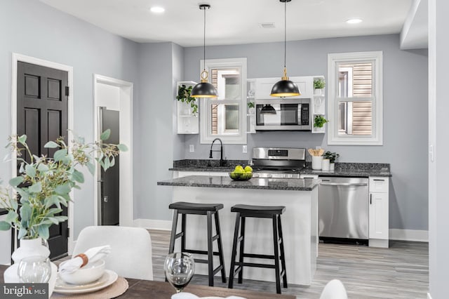 kitchen with a breakfast bar, a sink, a center island, appliances with stainless steel finishes, and white cabinets