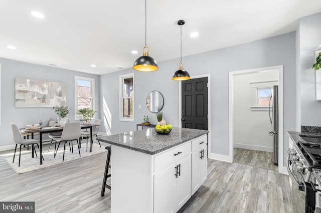 kitchen featuring stone counters, stainless steel appliances, a healthy amount of sunlight, and light wood-style flooring