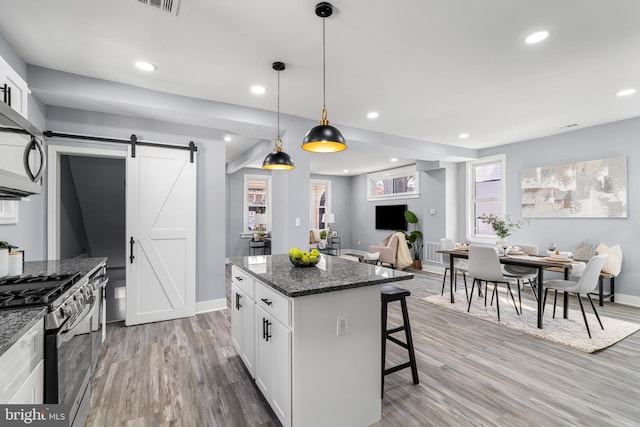 kitchen featuring open floor plan, a breakfast bar area, a barn door, light wood-style floors, and stainless steel appliances