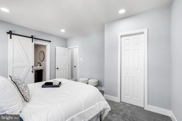 carpeted bedroom with ensuite bath, a barn door, recessed lighting, and baseboards