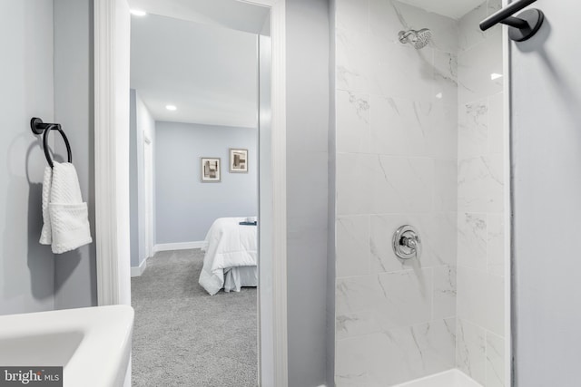 ensuite bathroom featuring a tile shower, ensuite bath, and baseboards