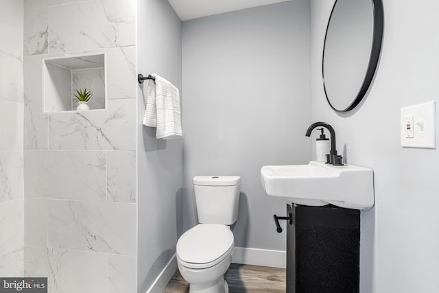 bathroom featuring a sink, toilet, baseboards, and wood finished floors