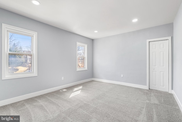 carpeted empty room featuring recessed lighting, visible vents, and baseboards