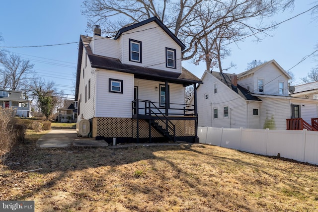 view of front of property featuring a porch, a chimney, and fence