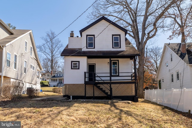 view of front of property featuring a porch, a chimney, a front yard, and fence