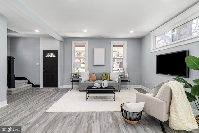 living room featuring stairway, plenty of natural light, baseboards, and wood finished floors