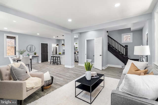 living area with stairway, recessed lighting, light wood-style floors, and baseboards