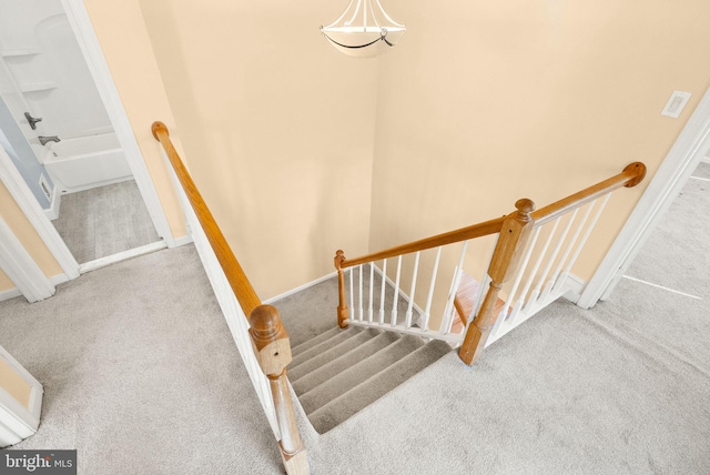 stairway featuring baseboards and carpet